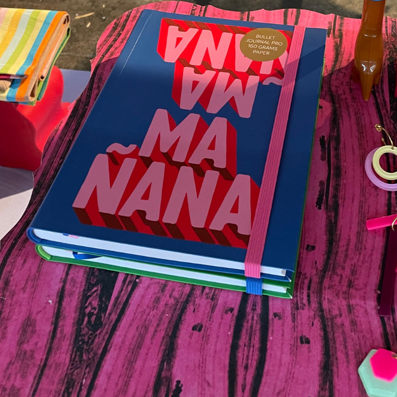 Blauw notitieboek met roze tekst op roze tafel