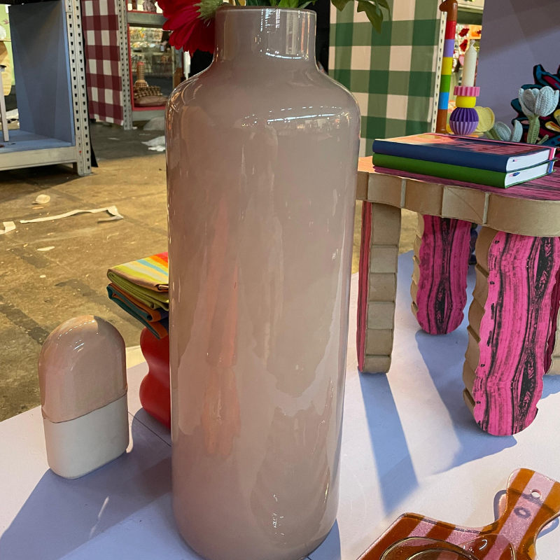 Grote glanzende beige vaas op kleurrijke tafel