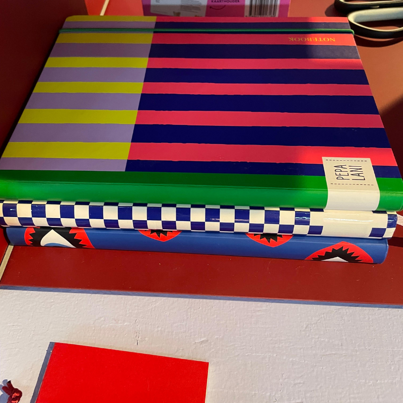 Stapeltje kleurrijke notitieboeken met opvallende patronen op een bureau