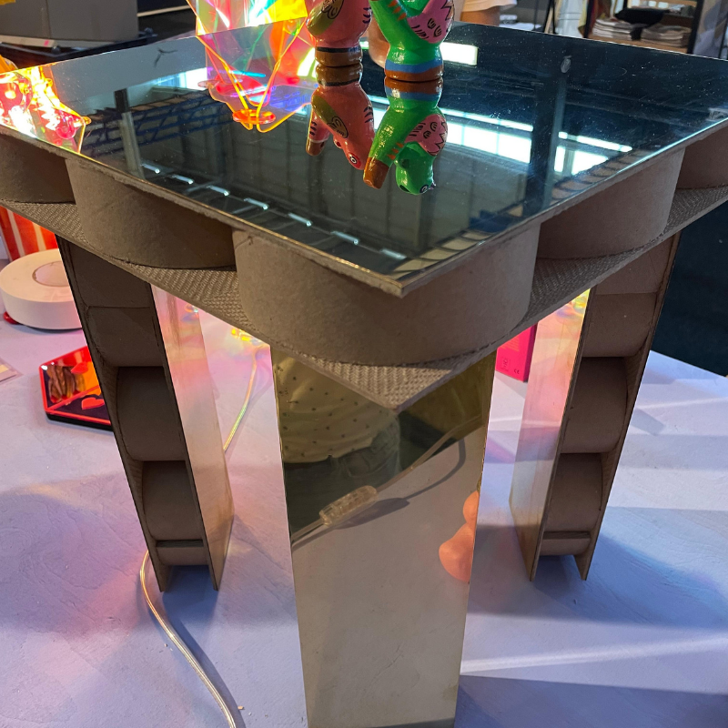 Kartonnen tafel met spiegelblad en kleurrijke speelgoedfiguren