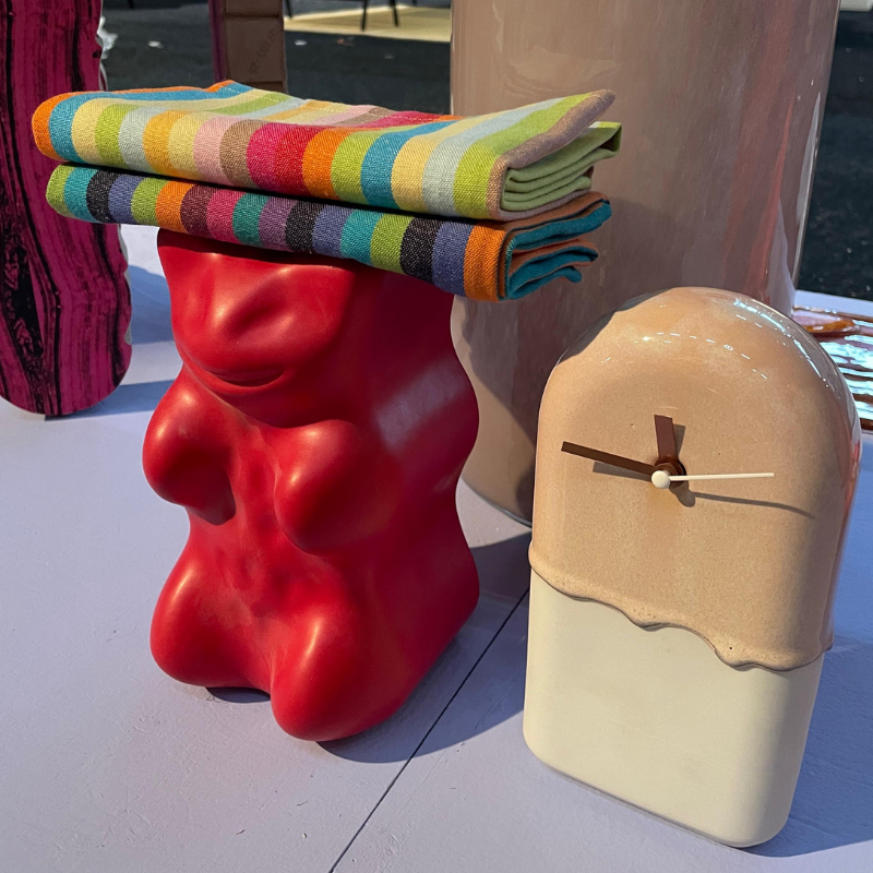 Rode sculpturale kruk met dekens naast keramische klok