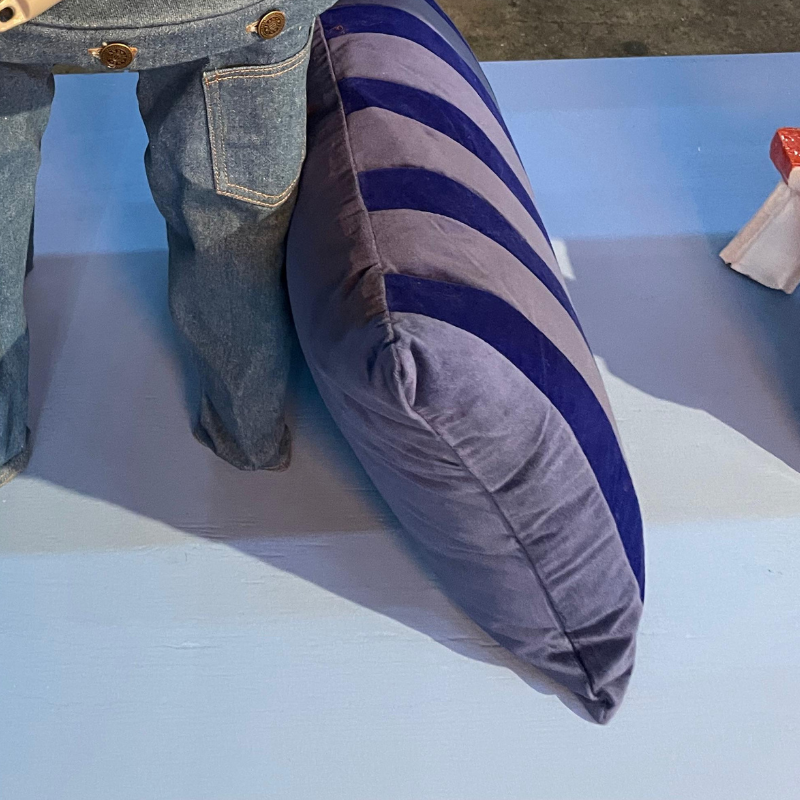 Gestreept blauwgrijs sierkussen naast denim kledingstuk