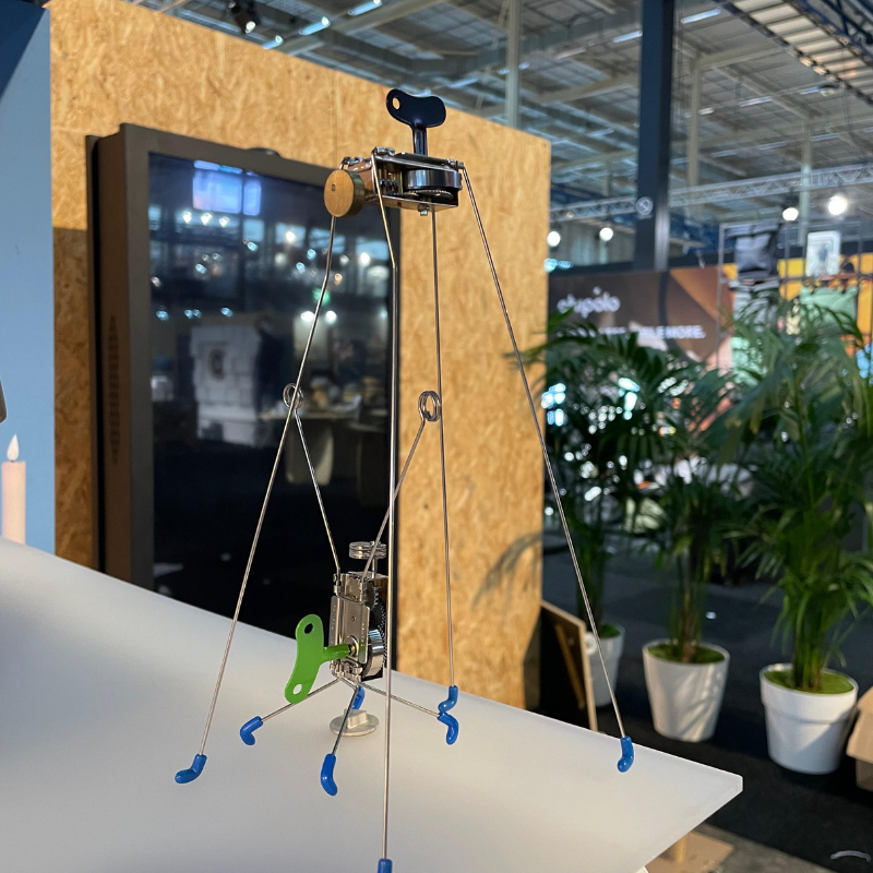 Kinetische metalen sculptuur met opwindmechanisme op beursstand
