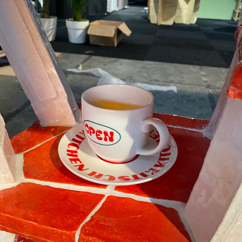 Koffiekopje met oranje drank op rood tegelplateau