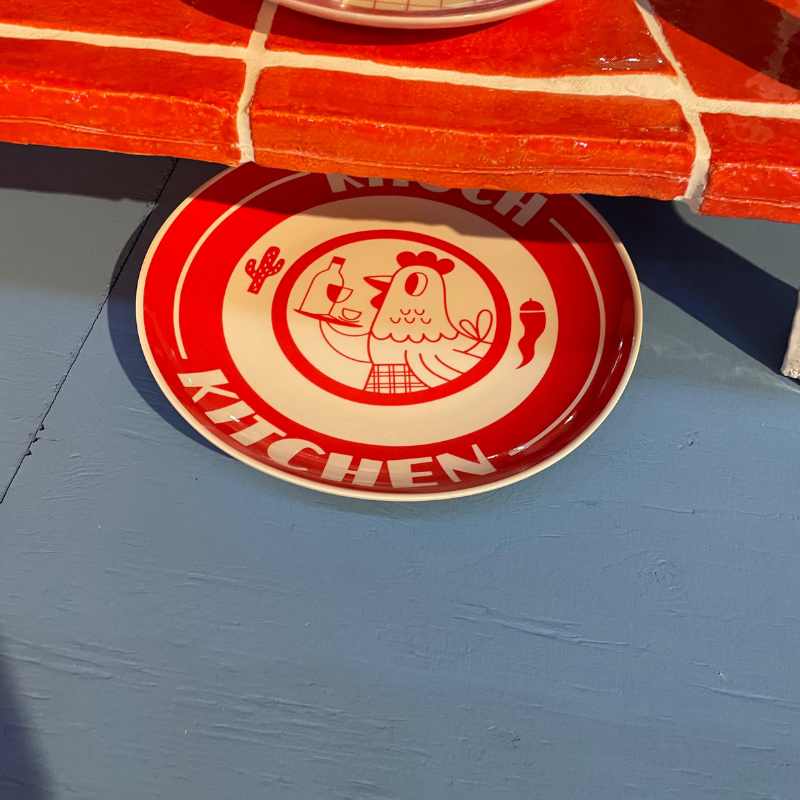 Rood bord met kipillustratie onder betegelde tafel
