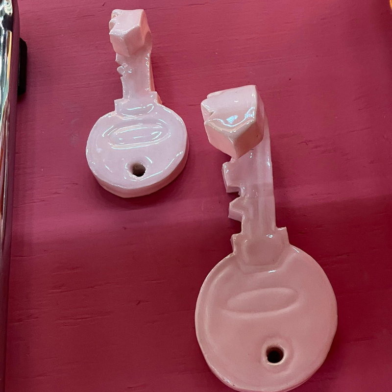 Twee roze keramische sleutelhangers op rood oppervlak