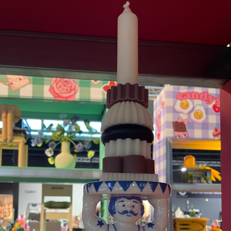 Decoratieve kandelaar met witte kaars en blauw figuurtje