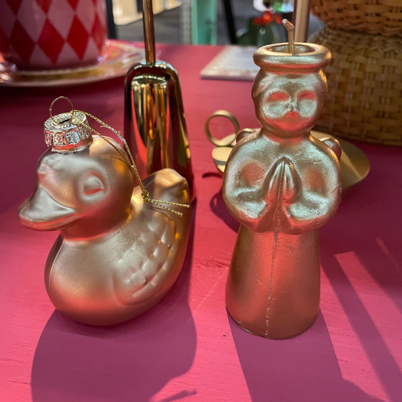 Gouden eendje en biddend engelfiguurtje op roze tafel