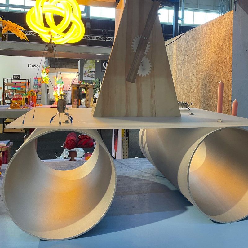 Houten kinetische installatie met buizen en gele neonlamp