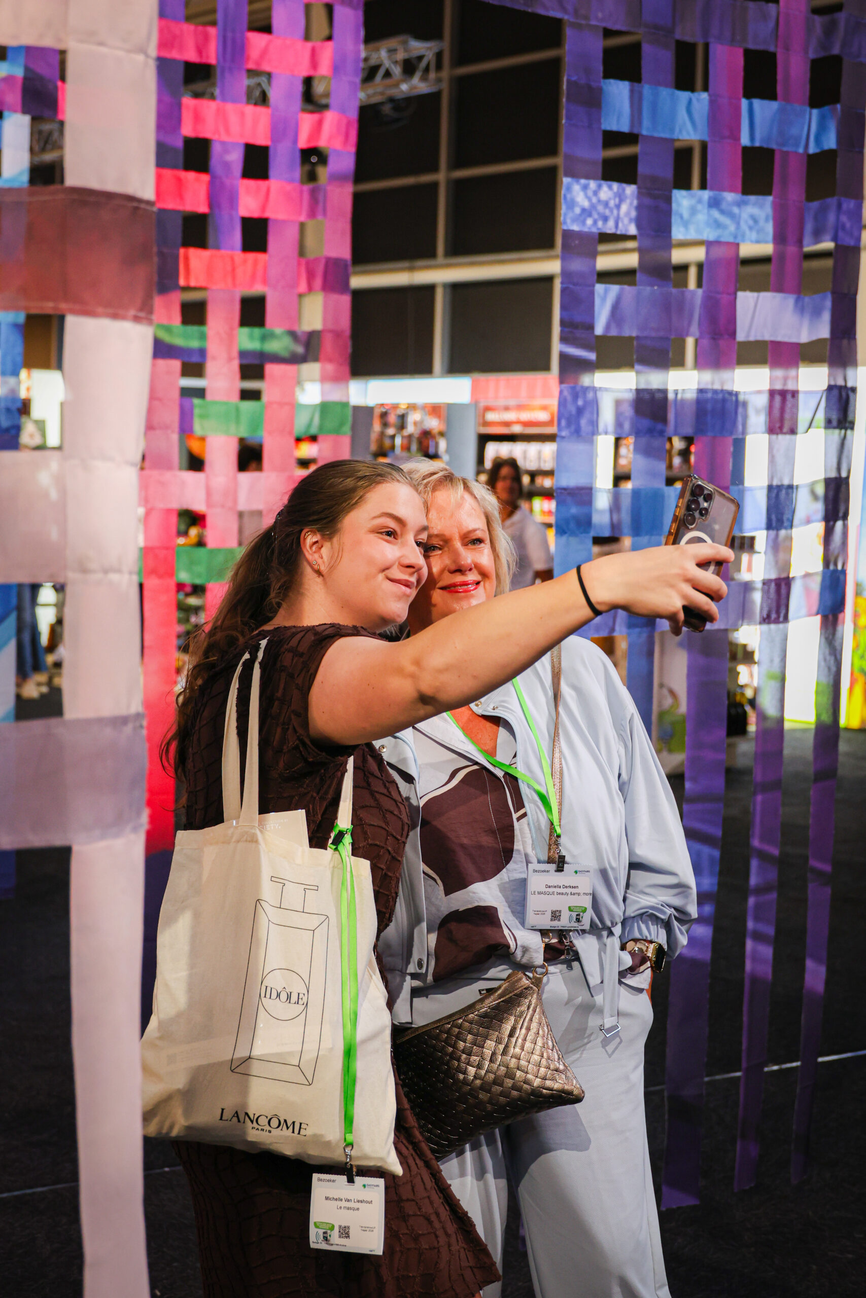 Twee vrouwen maken selfie bij kleurrijke linteninstallatie