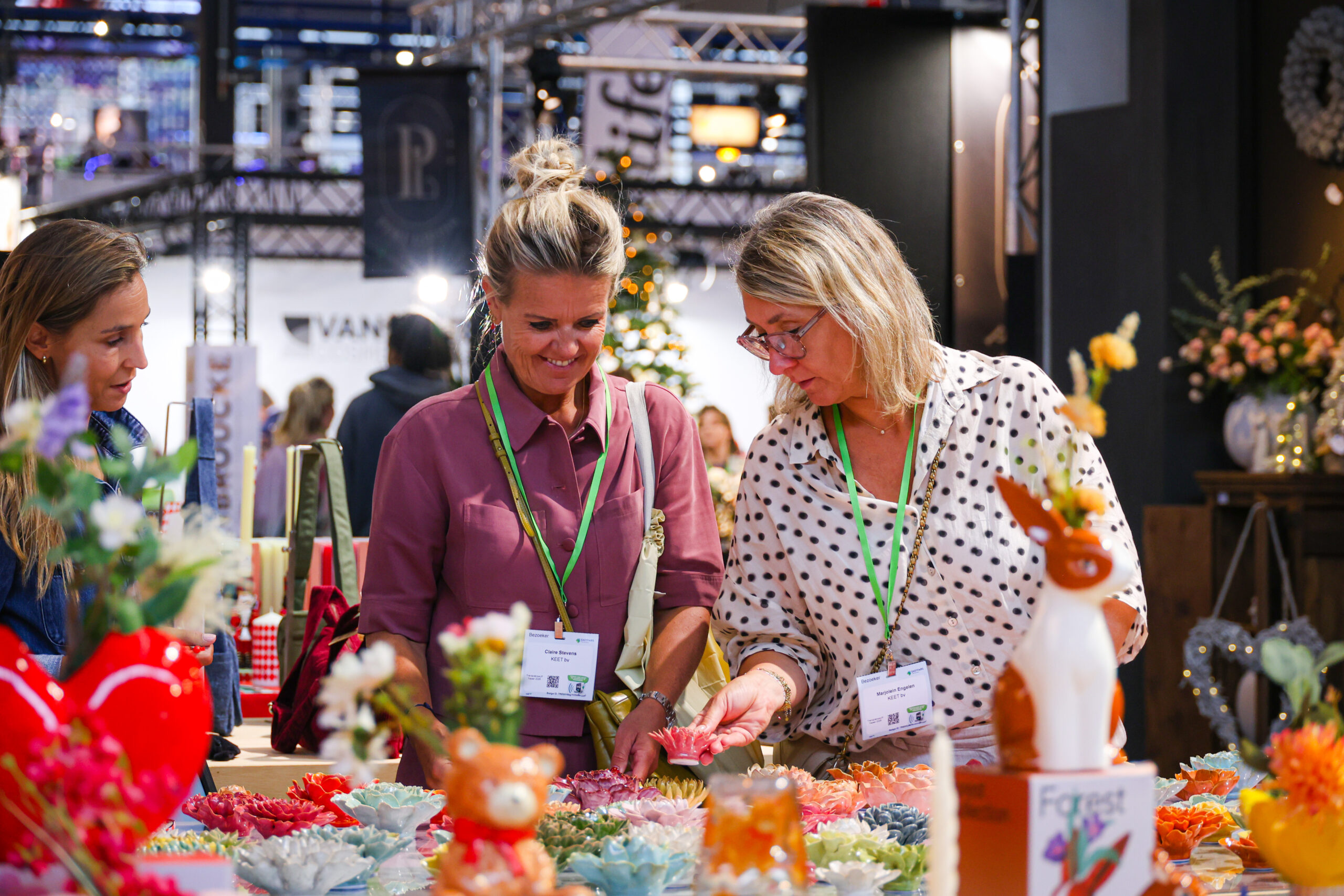Bezoekers bekijken kleurrijk keramiek op een beurs.