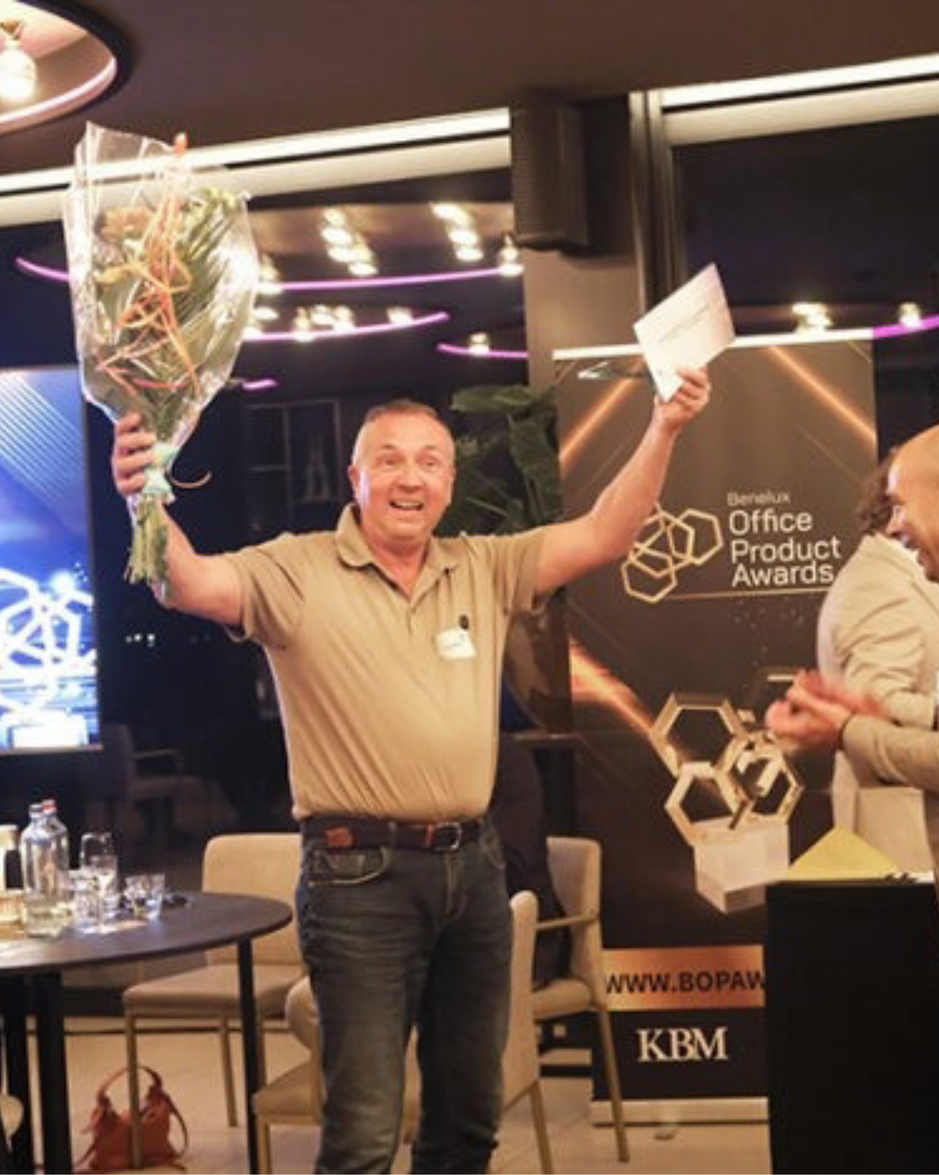 Blije man ontvangt bloemen en prijs bij kantooraward
