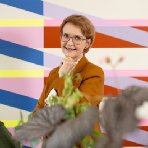 aafje Glimlachende vrouw voor kleurrijke geometrische muurschildering met planten