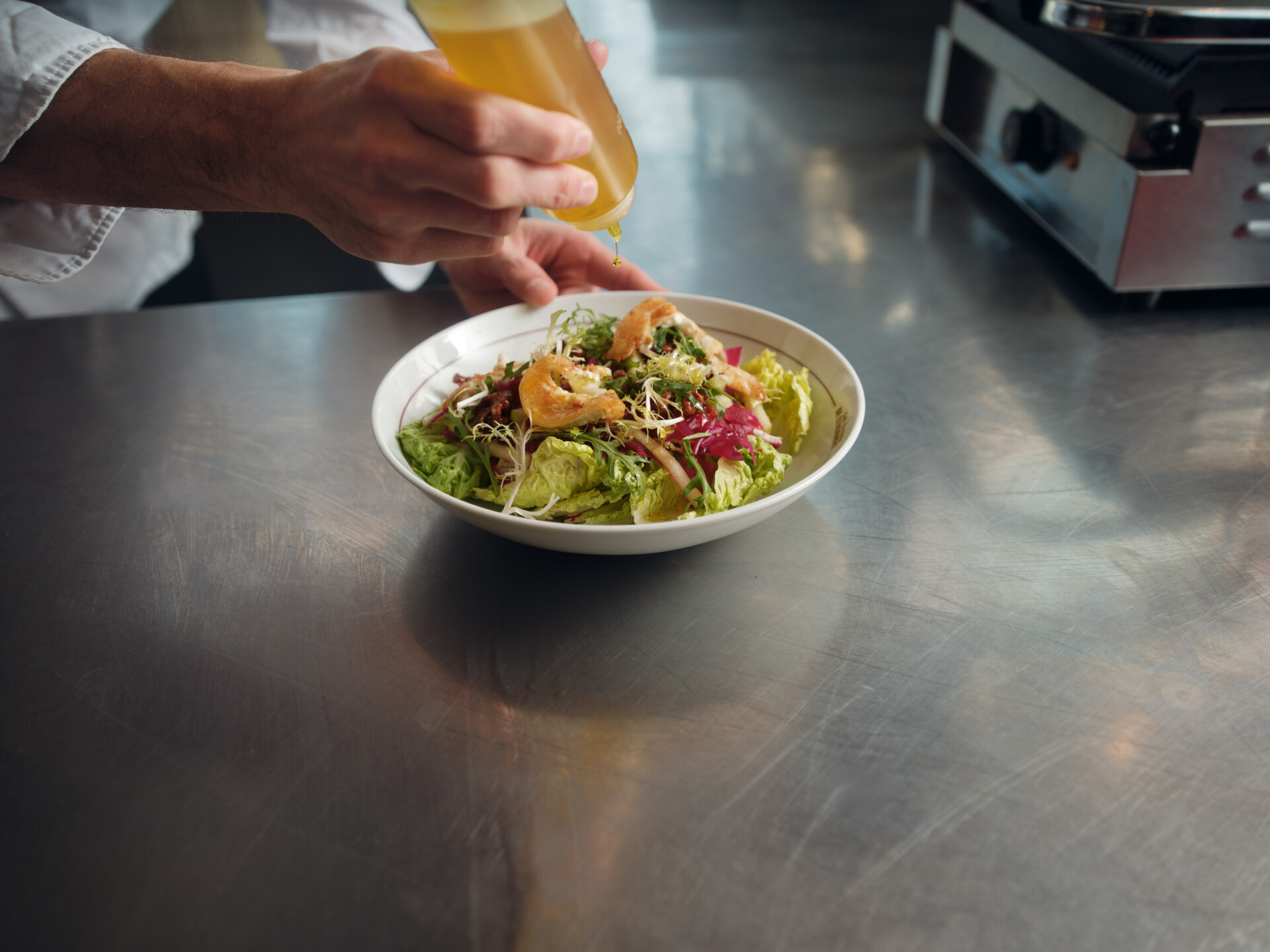 Chef besprenkelt verse salade met dressing