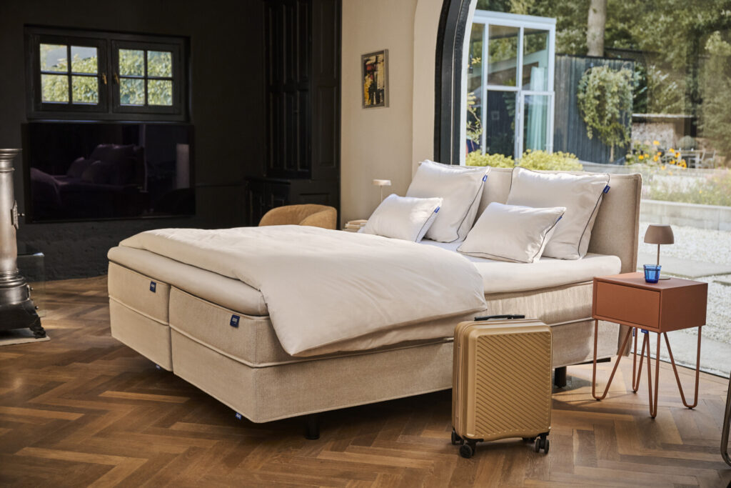 Beige bed met koffer in zonnige slaapkamer