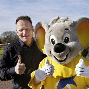 Man poseert met grijze muizenmascotte en duim omhoog