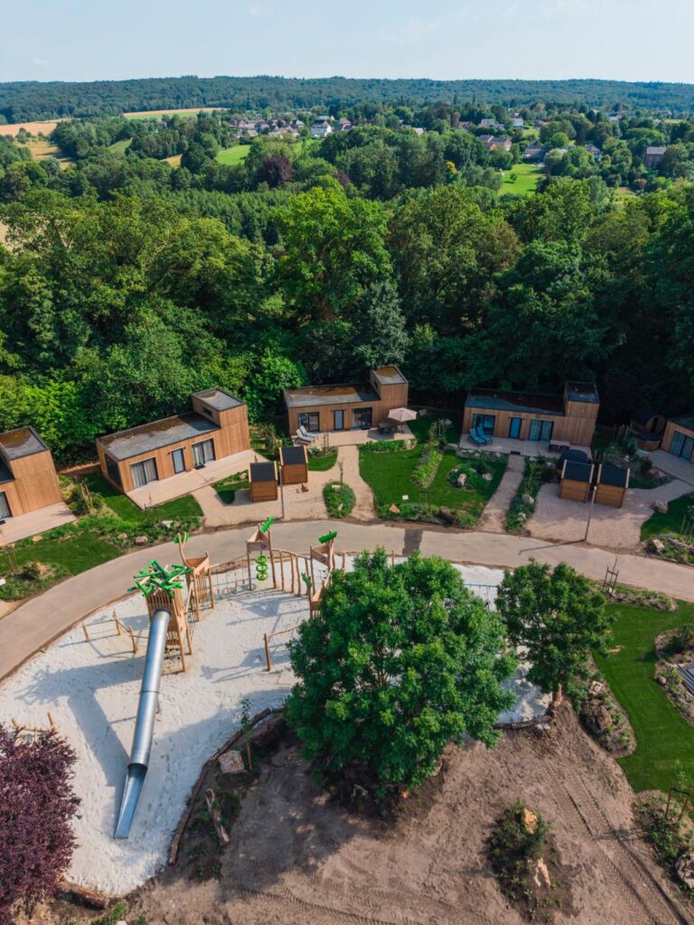 Luchtfoto van vakantiehuisjes, speeltuin en bosrijk dorp