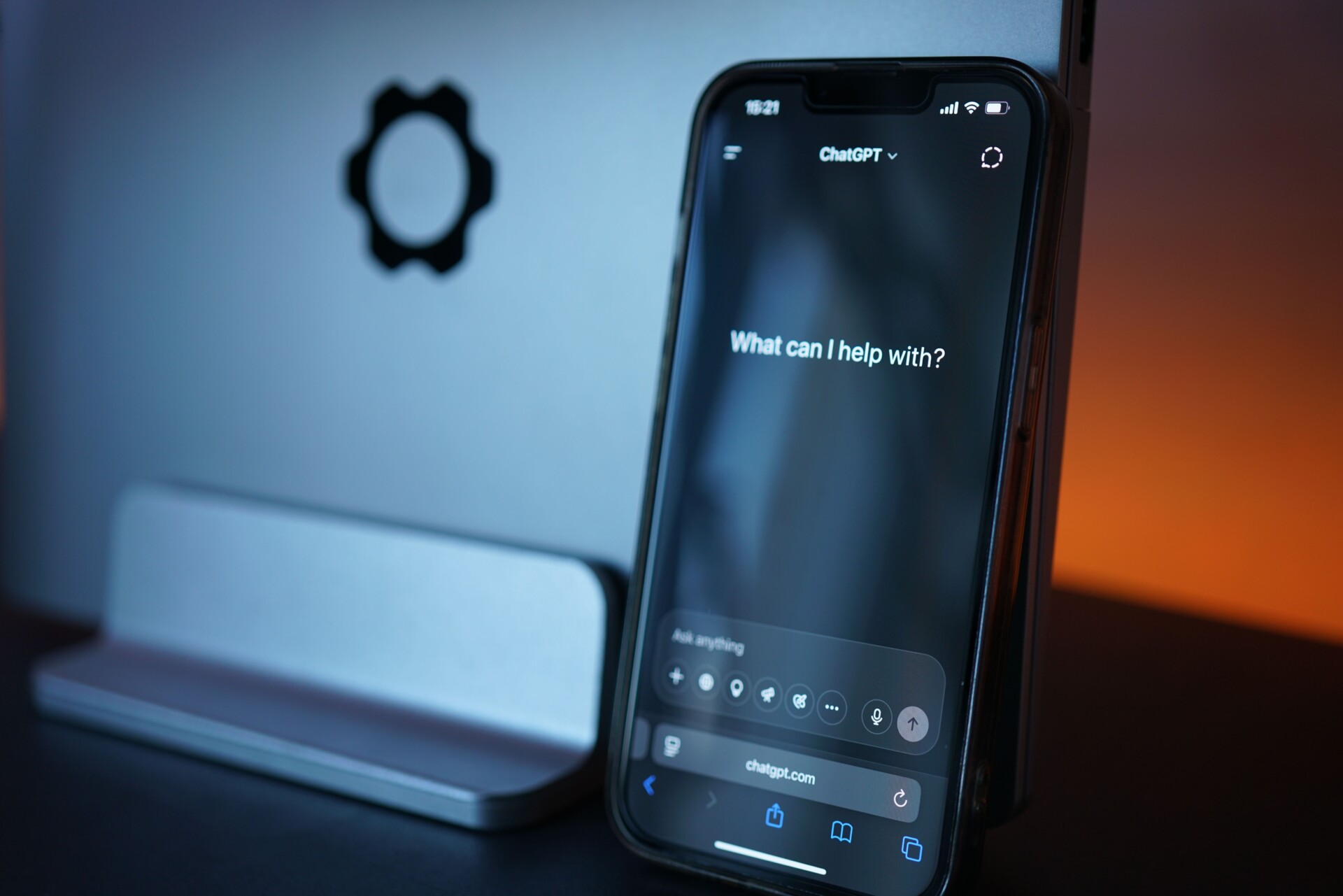 Smartphone met ChatGPT-interface naast laptop op bureau