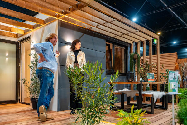 Twee mensen bij moderne houten tuinoverkapping met planten