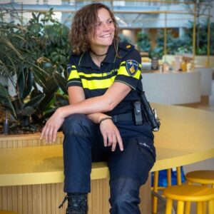 Glimlachende politieagent zit op gele bank binnen