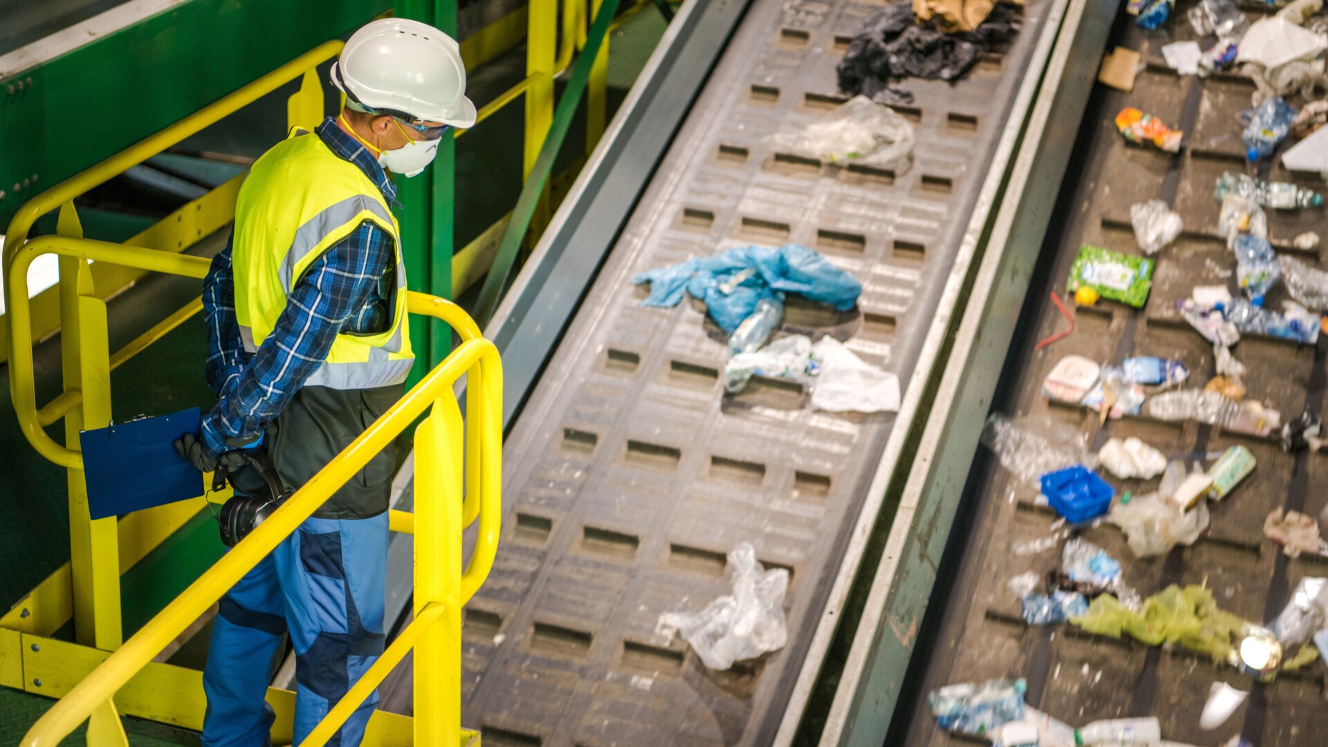 Werknemer inspecteert afval op transportband in recyclinginstallatie