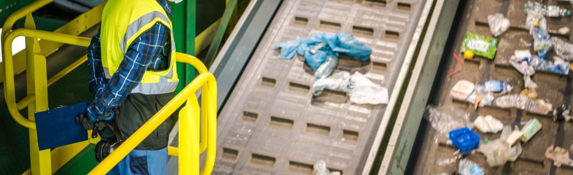 Werknemer inspecteert afval op transportband in recyclinginstallatie
