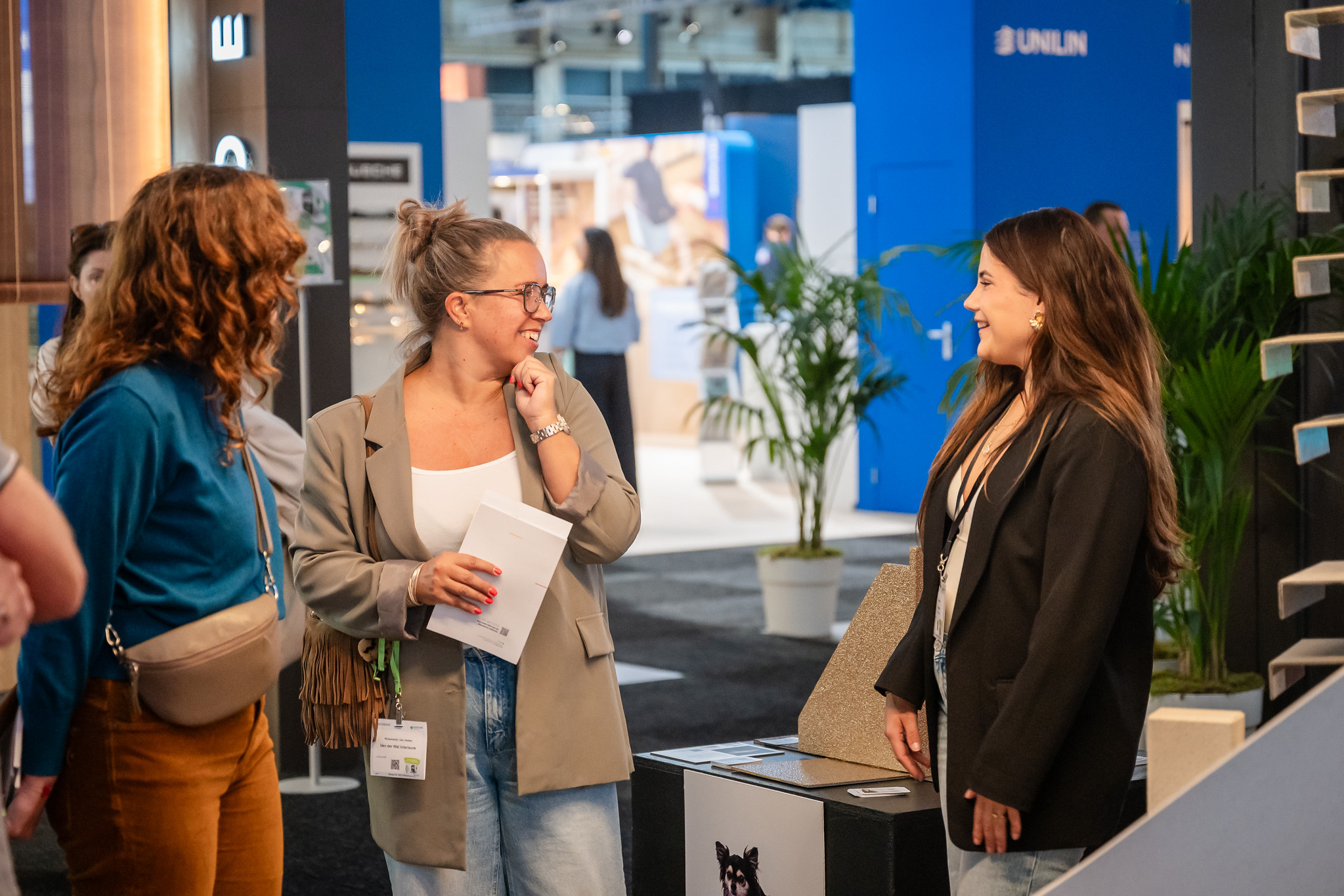 Drie vrouwen in gesprek op een beursstand