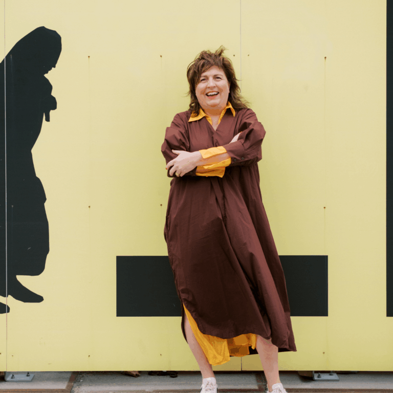 Lachende vrouw voor gele muur met zwarte silhouetkunst