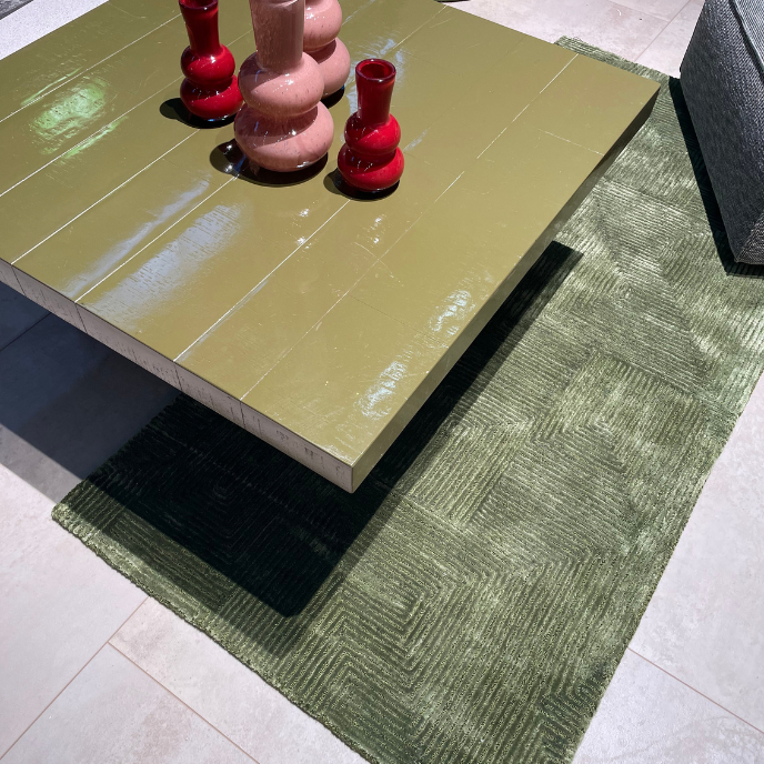 Olijfgroene salontafel op groen vloerkleed met vazen
