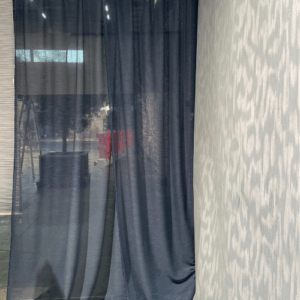 Donkerblauwe transparante gordijnen naast lichte wand