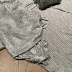 Grijze plaid met franjes op een licht houten vloer