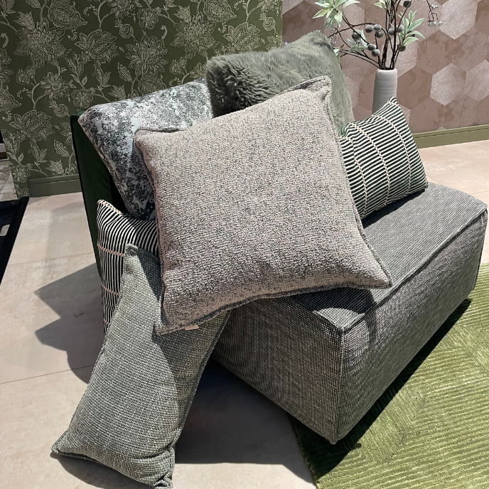 Grijze fauteuil met diverse sierkussens en groen vloerkleed
