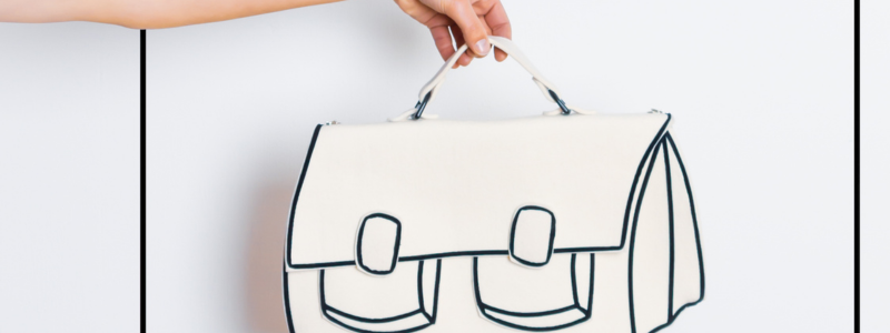 Hand houdt witte handtas met zwarte contouren vast