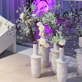 Witte bloemen en groen in marmeren vazen met paars licht