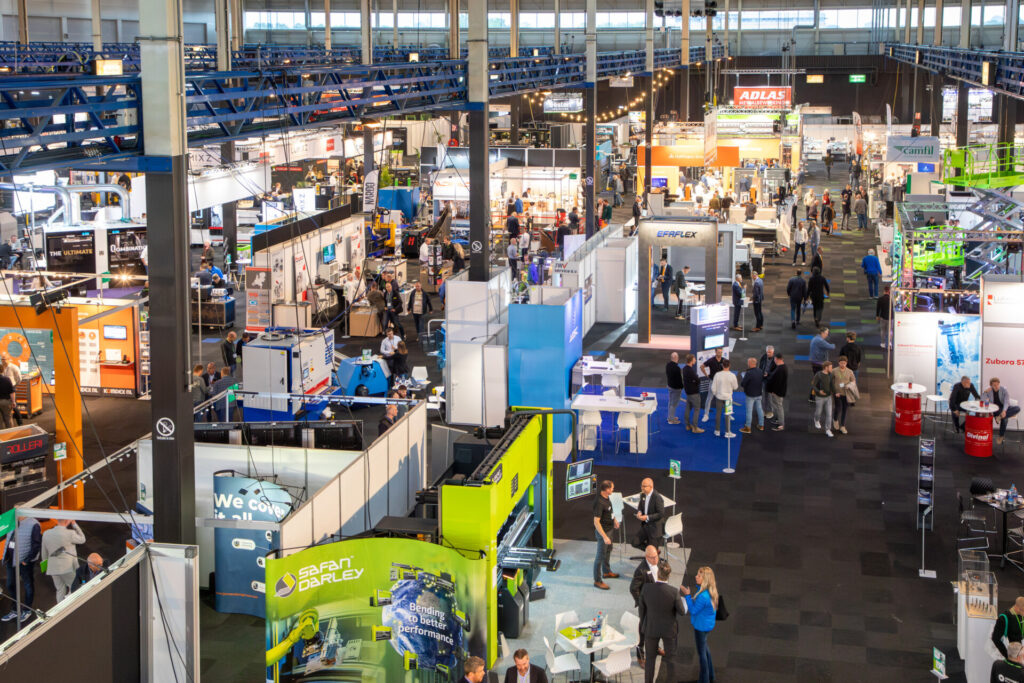 Drukke industriële vakbeurs met stands, machines en bezoekers