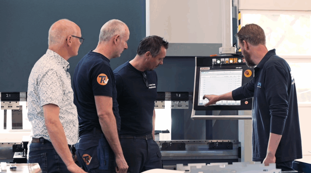 Vier mannen bedienen industriële machine met touchscreen