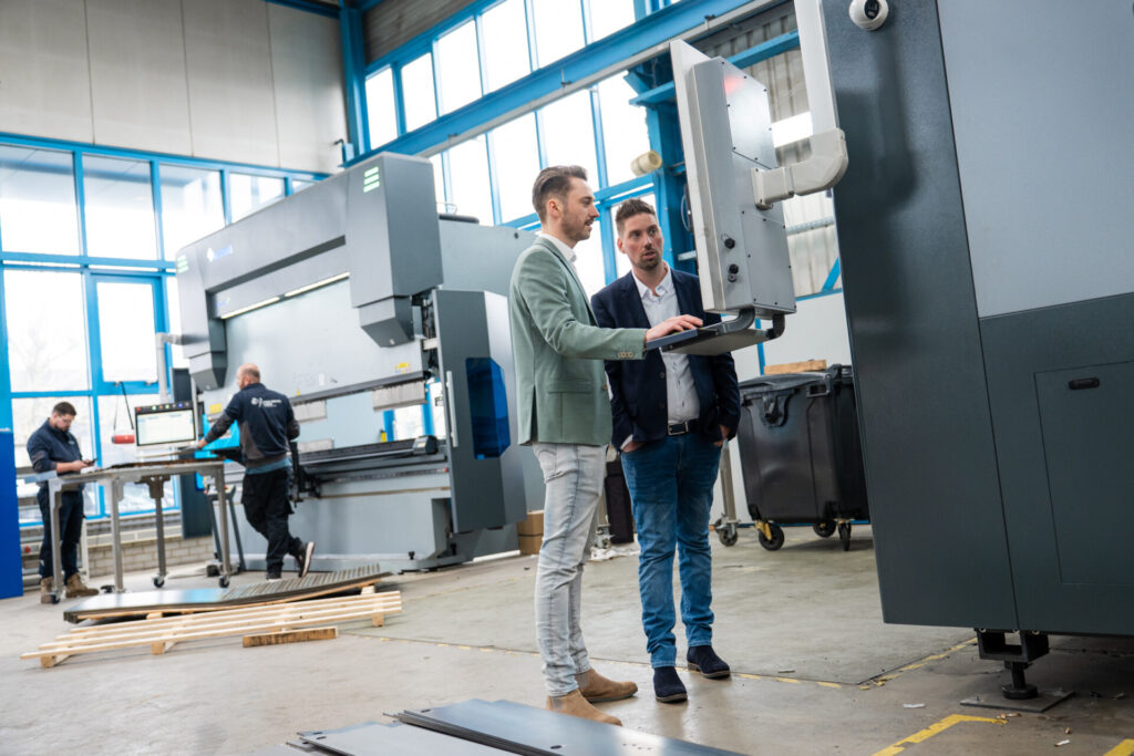 Twee mannen bedienen machine in moderne metaalwerkplaats