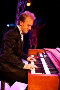 Man speelt keyboard op een verlicht podium