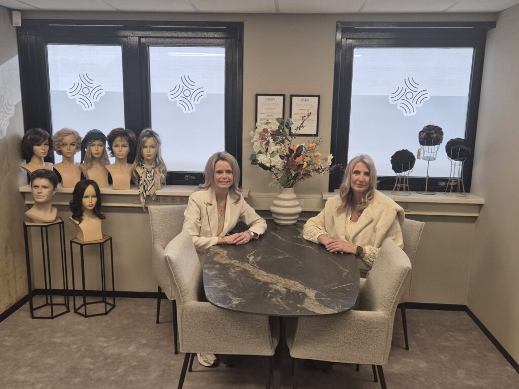 Twee vrouwen in pruikenstudio met etalagepoppen