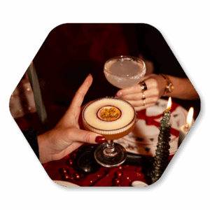 Twee handen proosten met cocktails bij kaarslicht