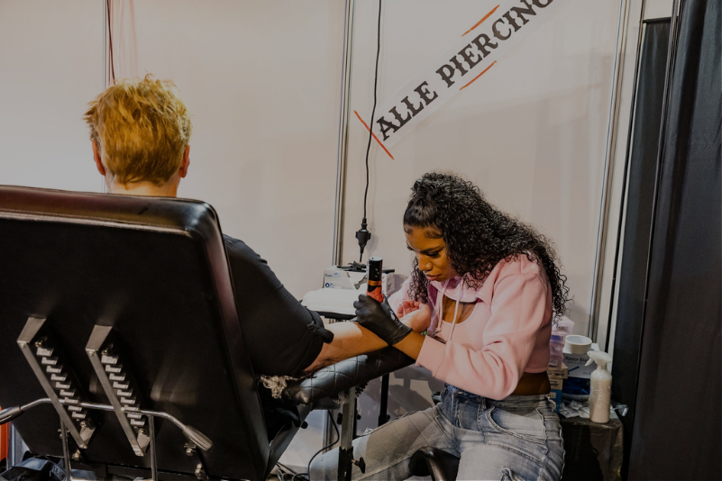 Tattooartiest zet tatoeage op arm van klant