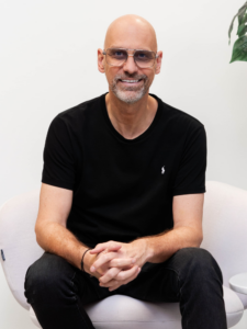 Glimlachende kale man met bril in fauteuil