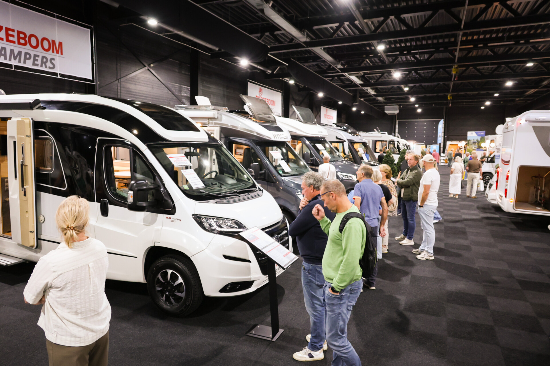 Bezoekers bekijken campers op een indoor camperbeurs.