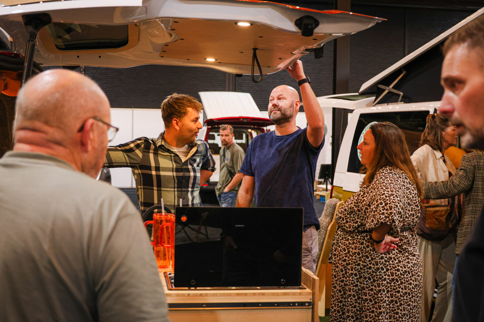 Bezoekers bekijken geopende achterklep van camper op beurs