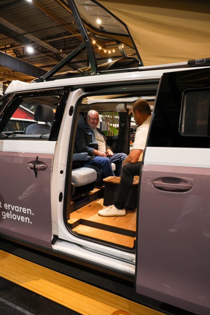 Twee mannen bekijken camperbus met hefdak op beurs