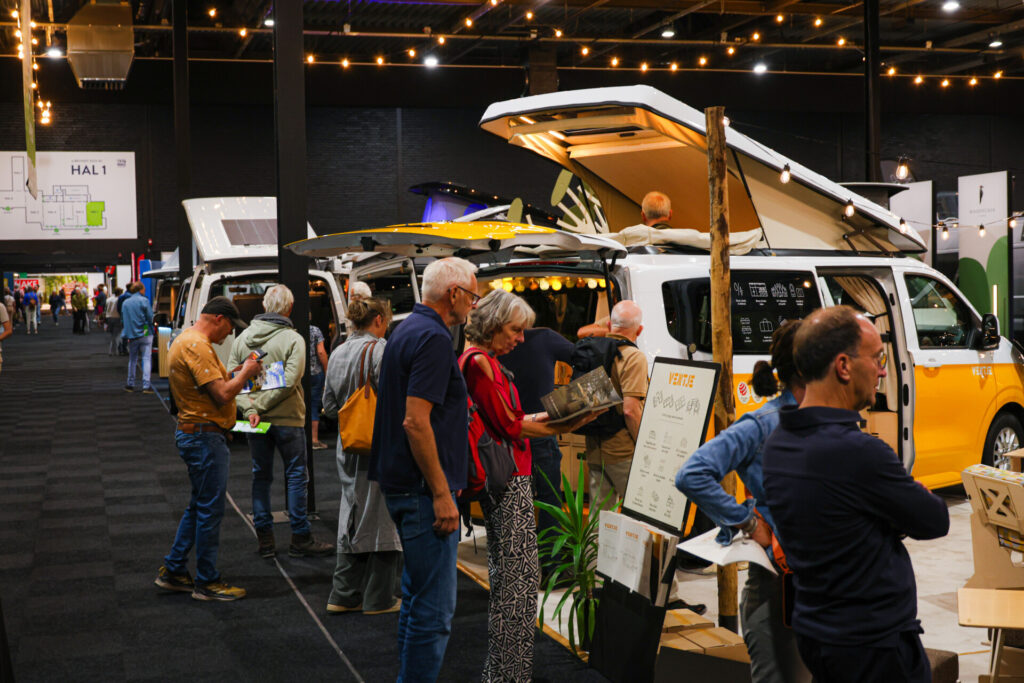 Bezoekers bekijken campers op een indoor kampeerbeurs