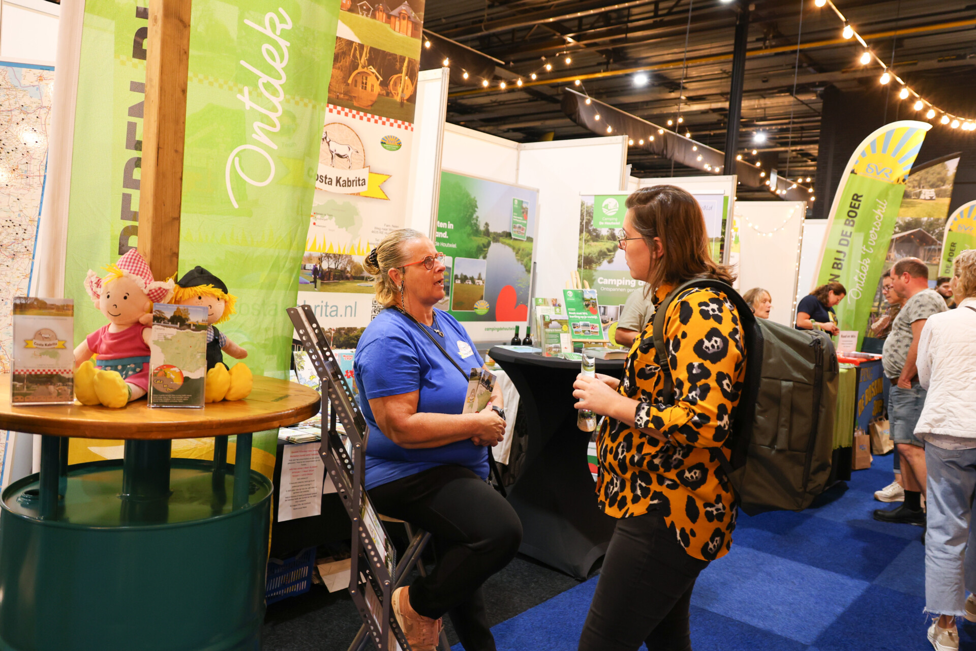 Bezoekers praten bij campingstand op een beurs