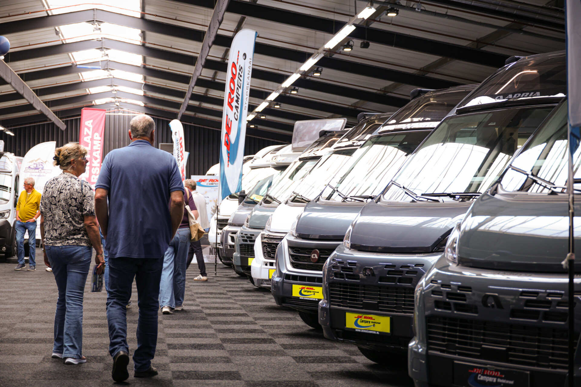 Bezoekers bekijken campers op een overdekte beurs