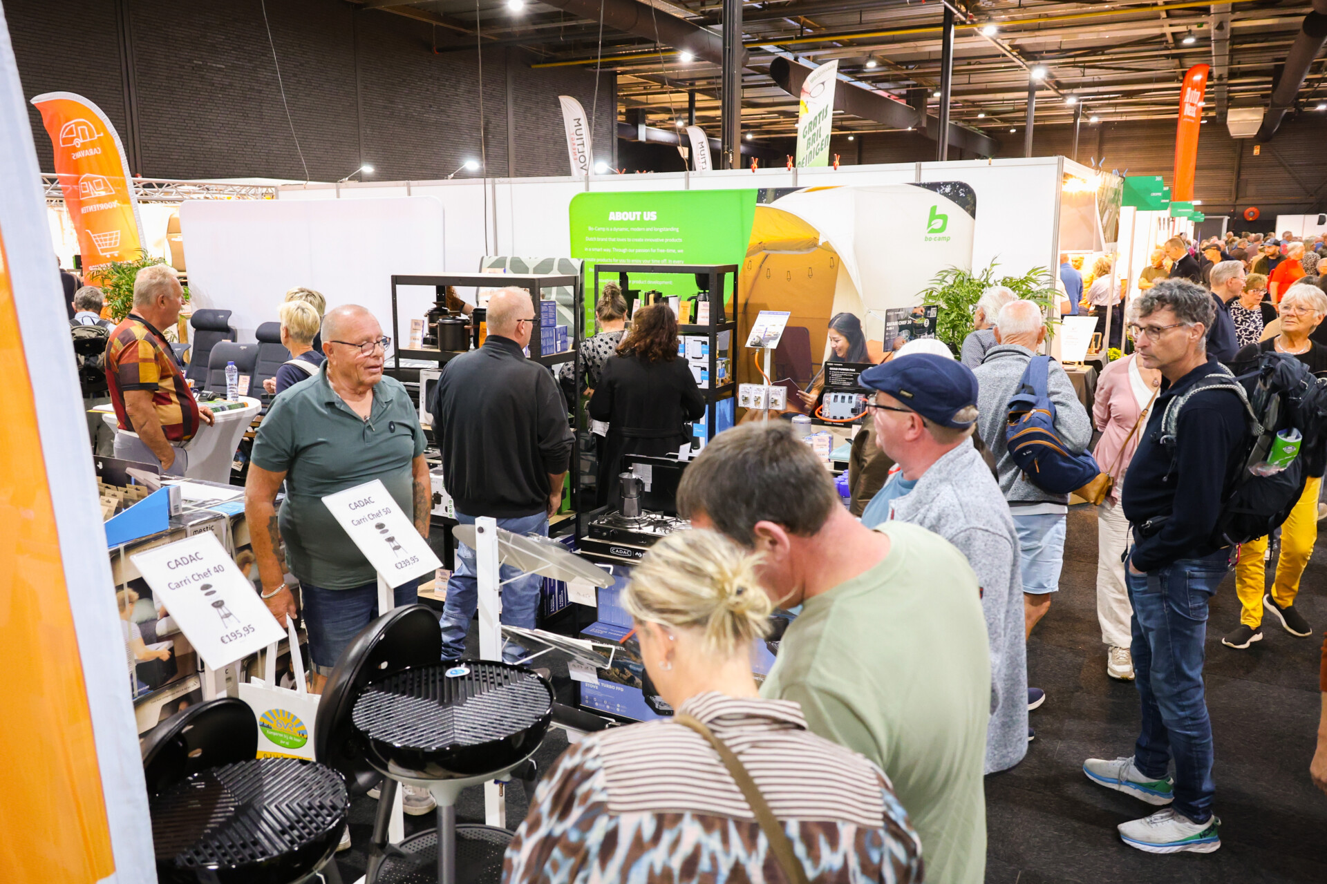 Bezoekers bekijken barbecues op drukke kampeerbeurs