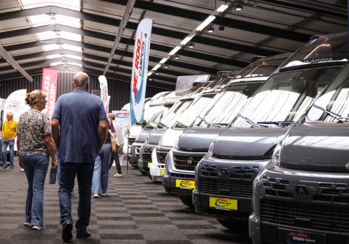 Bezoekers bekijken campers op een overdekte beurs